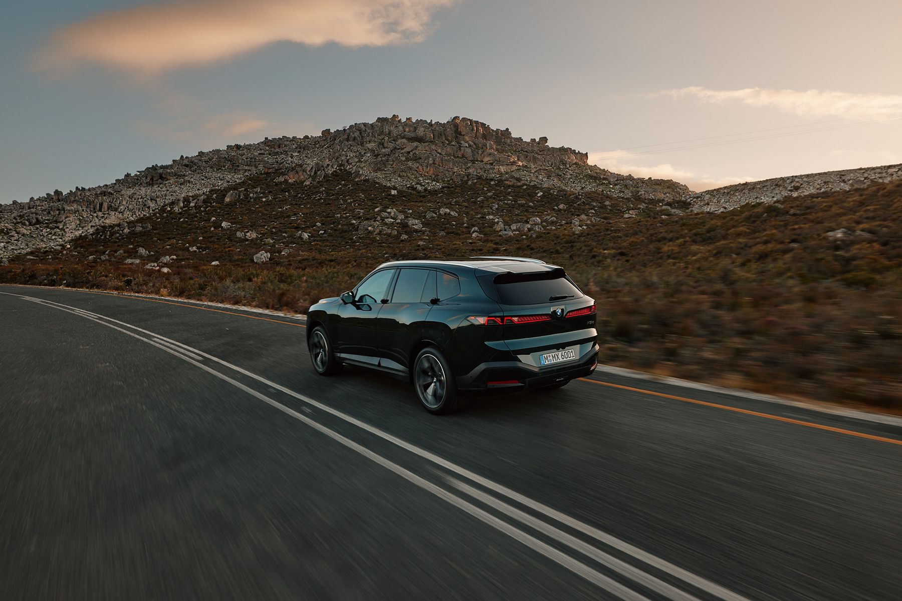 Der neue BMW X5 fährt auf einer Landstraße vor felsiger Hügelkulisse
