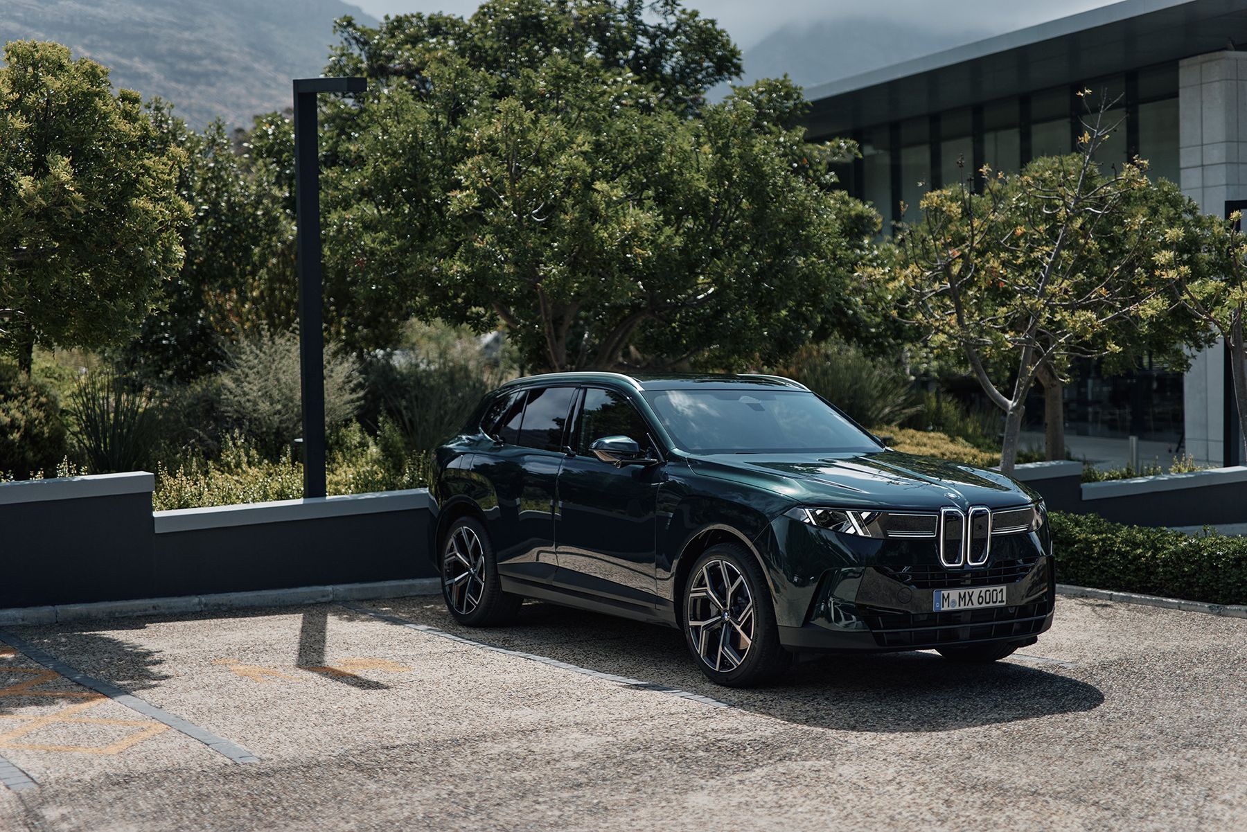 Der neue BMW X5 in dunkelgrüner Lackierung vor einem modernen Gebäude